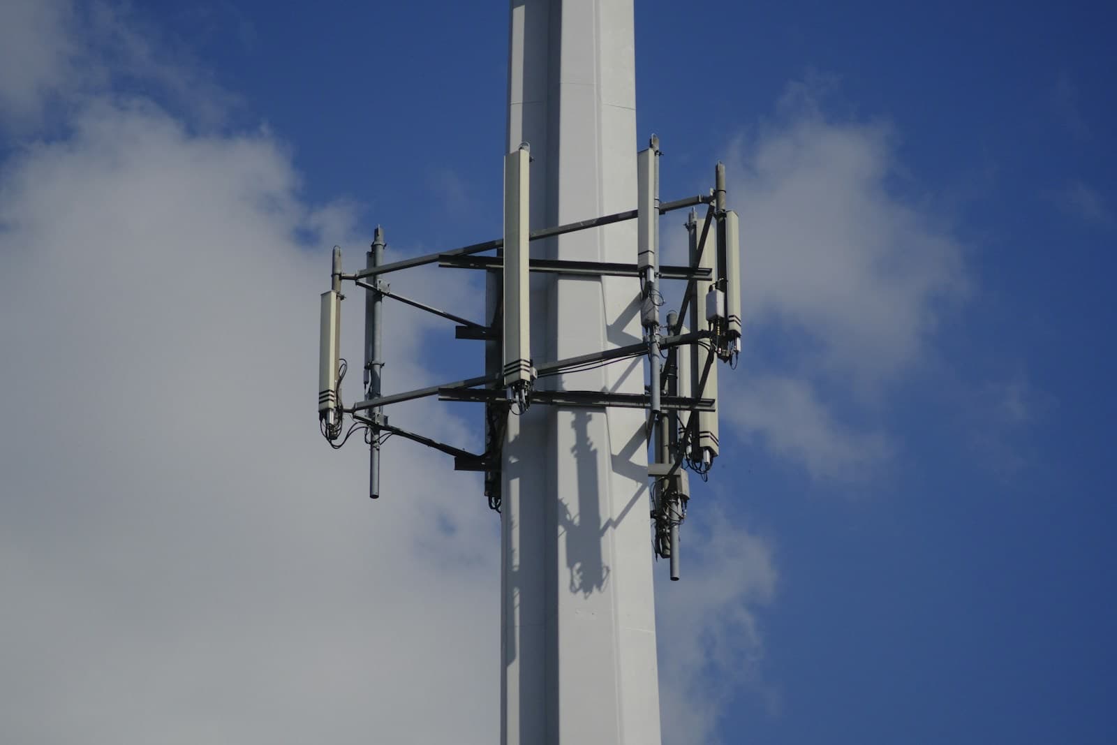 Panel antennas mounted on a white mast against a blue sky